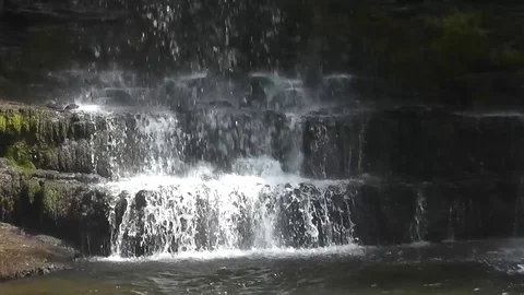 Smooth close-up of waterfall splashing onto mossy rocks Stock Footage 92576168