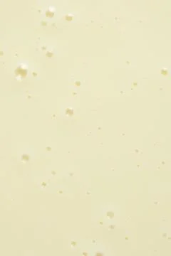 Smooth condensed milk texture with tiny bubbles macro. Stock Photos