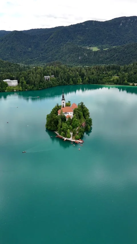 Smooth drone approach toward a small island on turquoise mountain lake Stock Footage 322045049