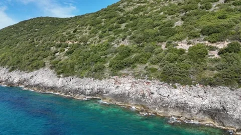 Smooth Drone Flight Along Rocky Coastline with Green Hills and Blue Sea Stock Footage 330882652