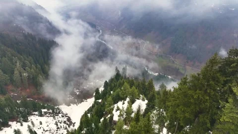 Smooth drone flight piercing low clouds over a moody mountain valley. Stock Footage 333801179