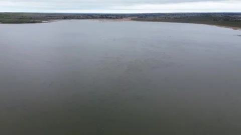 Smooth drone glide over a vast, moody lake towards the distant horizon Stock Footage 312417649