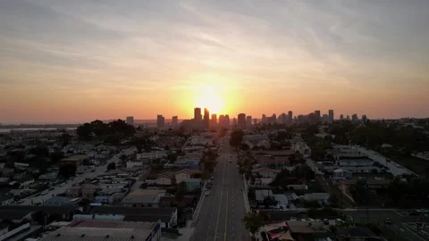 Smooth drone pullback shot from city skyline during sunset, showcasing glowing Видео 332686442