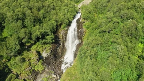 Smooth flight along large waterfall in the middle of the forest on a sunny Stockbeeldmateriaal 269298331