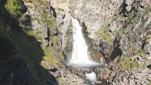 Smooth flight and ascent between the rocks to the waterfall above the river on a Stock Footage 269303447
