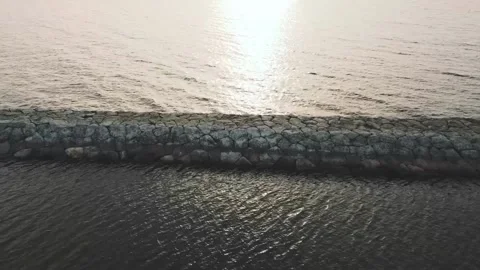 Smooth flight of the drone over the lake, in the middle there is a stone path Video stock 161433758