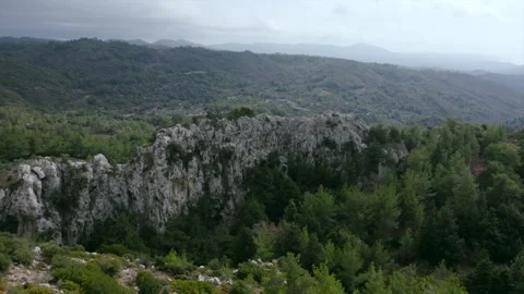 Smooth flight of a drone over a rock among a green forest Vídeos de archivo 169031844