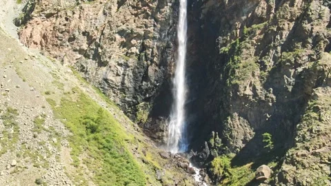Smooth flight in the mountains above the waterfall. A powerful stream breaks Stock Footage 277191300