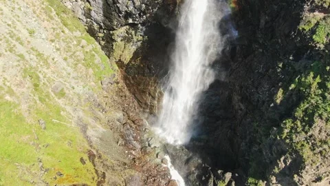 Smooth flight in the mountains above the waterfall. A powerful stream breaks Stock Footage 277191476