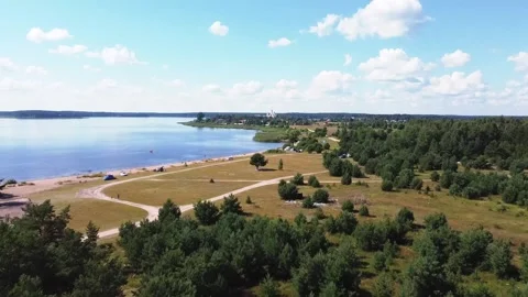 Smooth flight over green trees, bushes and a field, sandy roads on the field Video stock 163679122