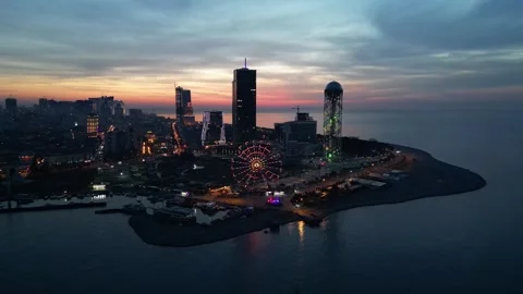 Smooth flight over the sea overlooking the cityscape at dusk Stock Footage 257466689