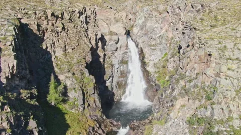 A smooth flight of the waterfall in a bowl between the rocks on a sunny day. Stockbeeldmateriaal 264093073