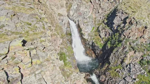A smooth flight of the waterfall in a bowl between the rocks on a sunny day. Stock Footage 264093138