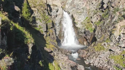 A smooth flight of the waterfall in a bowl between the rocks on a sunny day. Stockbeeldmateriaal 264093186
