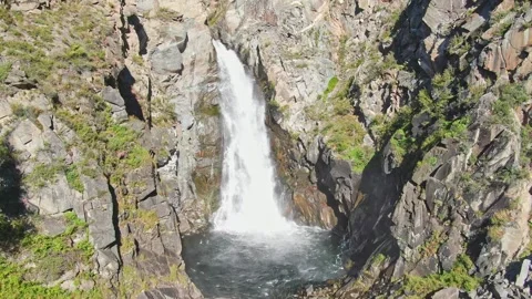 A smooth flight of the waterfall in a bowl between the rocks on a sunny day. Stock Footage 269302125