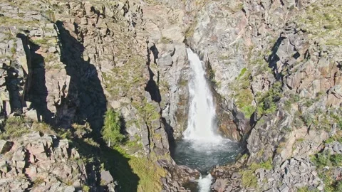 A smooth flight of the waterfall in a bowl between the rocks on a sunny day. Stock Footage 269302742