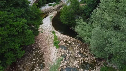Smooth Forward Flight Over River Revealing Historic Stone Bridge and Wooded Stock Footage 319995030