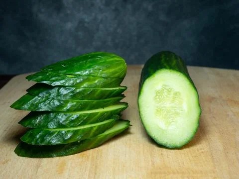 A smooth, medium-sized cucumber cut into slices. Cucumber on a cutting board. Stock Photos