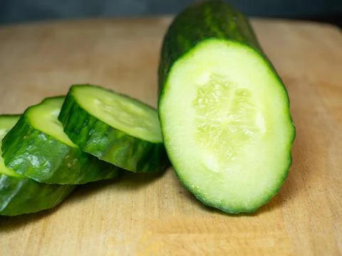 A smooth, medium-sized cucumber cut into slices. Cucumber on a cutting board. Stock Photos