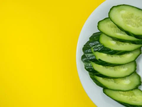 A smooth, medium-sized cucumber on a plate, sliced. Cucumber on a yellow back Stock Photos