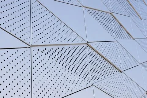 Smooth metal wall with triangular pattern and round openings Stock Photos