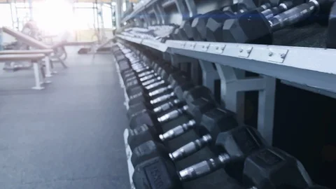 Smooth movement. Movement over the rack with metal dumbbells. Beautiful light Stock Footage 116604451