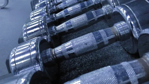 Smooth movement. Movement over the rack with metal dumbbells. Beautiful light Stock-Footage 117938523