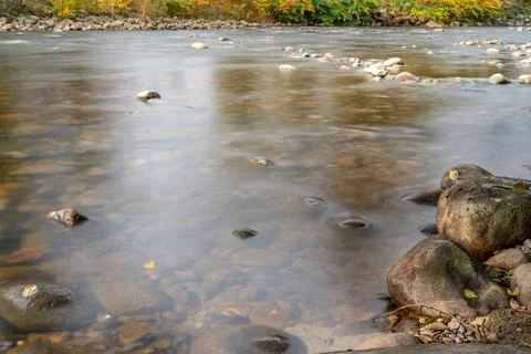 Smooth River Flow over Rounded Stones in Autumn  Long Exposure Fotos de archivo