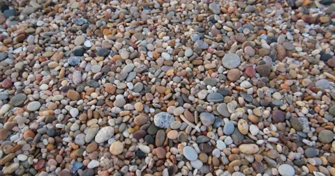 Smooth round pebbles on beach. Slow pull back, tilt up. Stock Footage 146055106