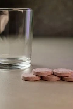 Smooth round tablets arranged invitingly next to a clear glass Stock Photos