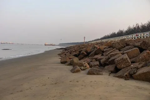 Smooth sandy tide pooling between rocks with cargo ships in background, Bang Foto stock