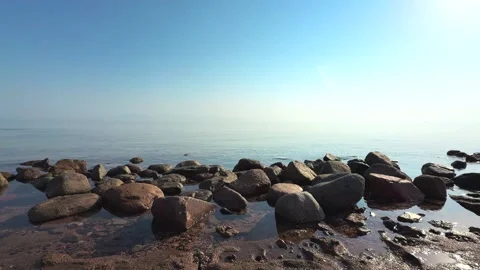 Smooth Sea Surface Reflecting Sunrise with Rocks in Foreground. Beautiful Stock Footage 340947357