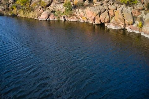 A smooth shining stream flows among large boulders Stock Photos