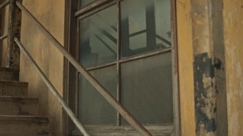 Smooth slider shot of dirty windows and metal railings in a decaying building Stock Footage 327688316