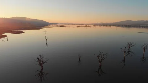 Smooth still lake at sunset showing wide vista with tree reflections. Stock Footage 108557216