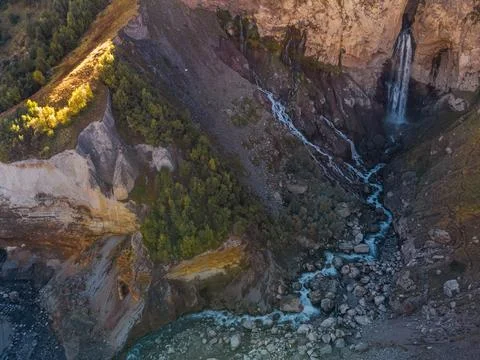 A smooth stream of water flows down from a cave in the high rocks of the Cauc Stock Photos