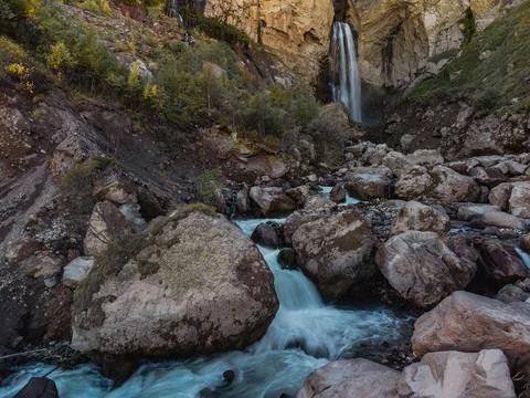 A smooth stream of water flows down from a cave in the high rocks of the Cauc Stock Photos