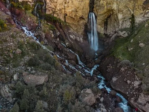A smooth stream of water flows down from a cave in the high rocks of the Cauc Stock Photos