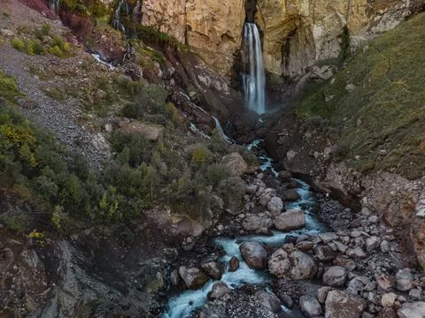 A smooth stream of water flows down from a cave in the high rocks of the Cauc Stock Photos