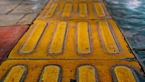 Smooth tilt up camera movement revealing tactile paving tiles and yellow gu.. Stock Footage 342037167