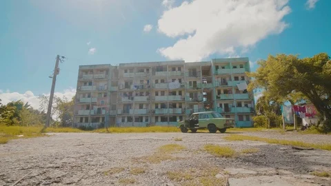 Smooth tracking shot of a large block of flats with an old car parked in front Stock Footage 88764696
