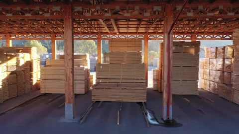 Smooth tracking shot through a lumber warehouse with stacks of finished wood 스톡 동영상 316032560
