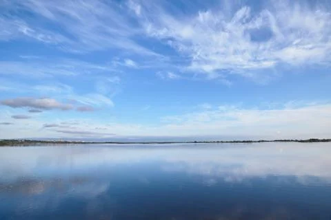 Smooth water surface under blue sky Stock Photos