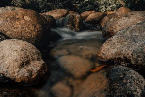 Smooth waterfall on dark-colored rocks Stock Photos