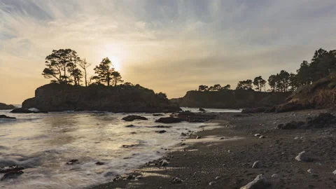 Smooth waves as the sunsets over a silhouetted island on coast - timelapse Vídeos de archivo 219353405