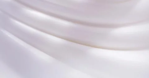 Smooth white fabric draped in soft waves under gentle light in a simple setting Stock Photos