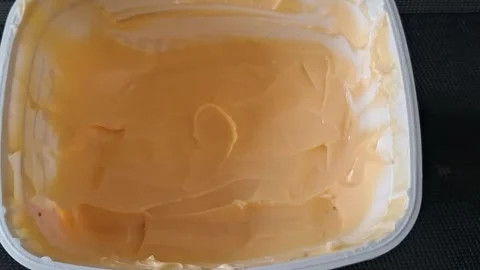 Smooth yellow butter spread in plastic container motion video footage Stock Footage 339248205