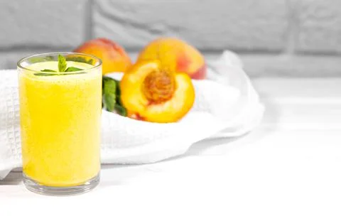 Smoothie with peach and mint leaf with piece of cloth on white brick backgrou Stock Photos
