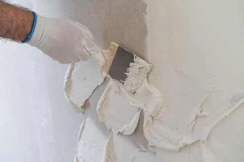 Smoothing surface with putty knife during drywall finishing process in Stock Photos