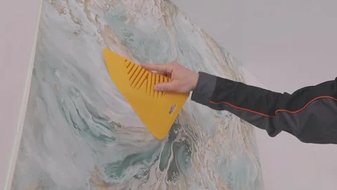 Smoothing wallpaper onto the wall to remove air bubbles. Stockbeeldmateriaal 335619854